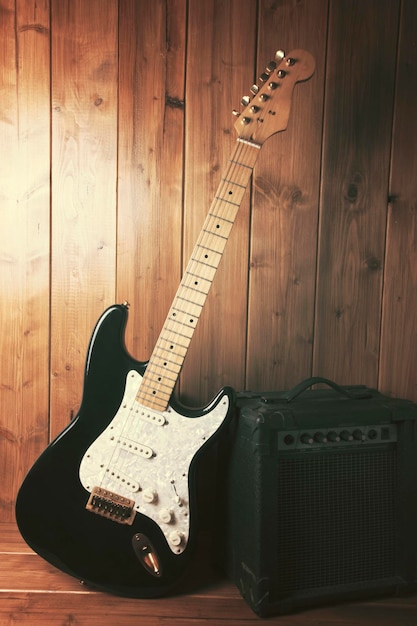 Gitaar met versterker op houten vloer