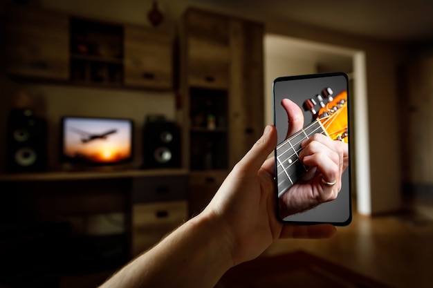 Gitaarlessen tutorial met smartphone. indoor screenshot van muzikale cursus.