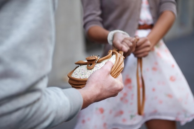 Restituiscilo immagine ritagliata del primo piano di una donna che si fa strappare la borsa da un criminale