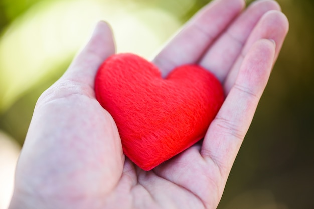 Foto give love man holding piccolo cuore rosso nelle mani per amore san valentino dona aiuto fai attenzione al calore dell'amore