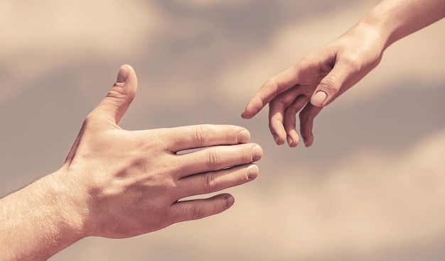 Фото Протягивая руку помощи руки мужчины и женщины на фоне голубого неба протягивая руку помощи руки мужчины и женщины тянутся друг к другу, поддерживают солидарность, сострадание и спасение милосердия