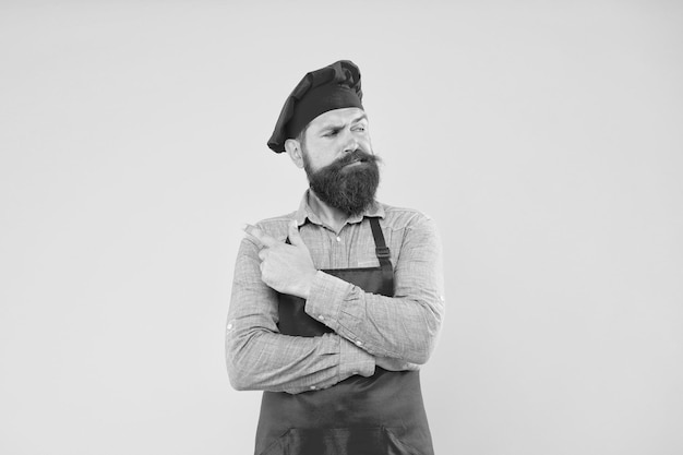 ケータリング ソリューションを提供するひげを生やしたシェフ ポインティング指の残忍な男性コック帽子とエプロン プロの男性料理レストランの料理と料理のケータリング ビジネス会社私たちのカフェへようこそ