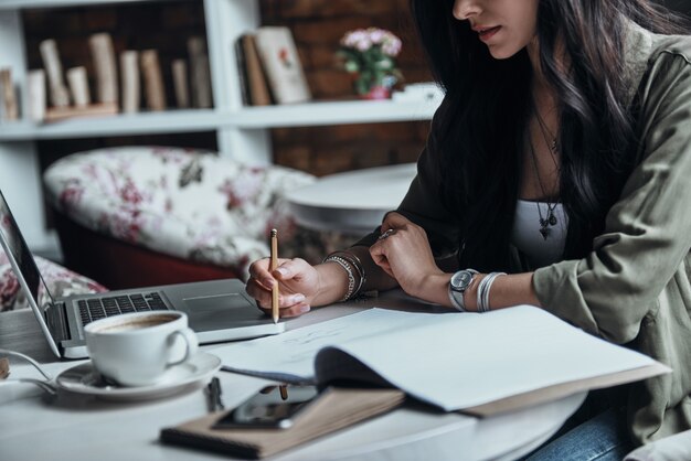 彼女のアイデアに出口を与える。何かを書き留める思いやりのある若い女性のクローズアップ