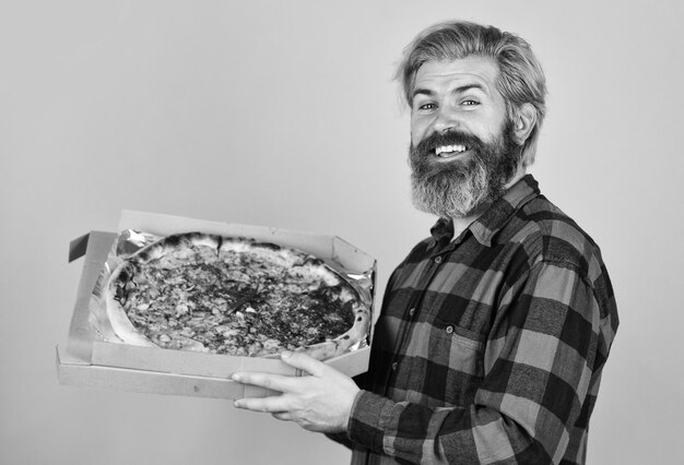 Photo giving food order and holding pizza hungry man eating pizza fast food delivery eating delicious cheesy pizza happy bearded man italian food italy is here cooking food concept
