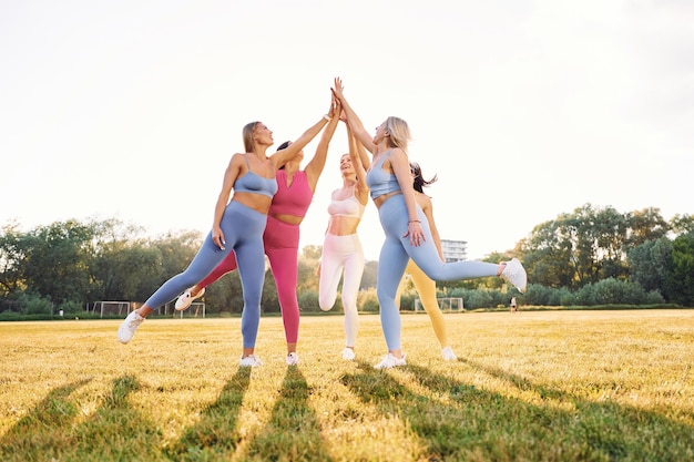 Giving high five Group of women have fitness outdoors on the field together