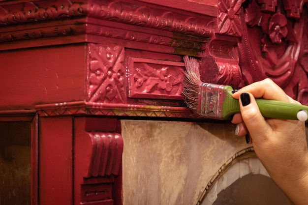 Giving new life to antique wooden ornamented cupboard by coloring it in red color with big brush Reuse of old things Home furniture renovation workroom