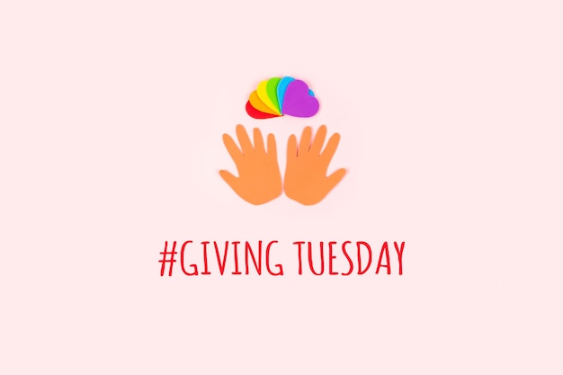 Giving tuesday concept minimal flat lay with text giving\
tuesday paper palms and rainbow hearts on