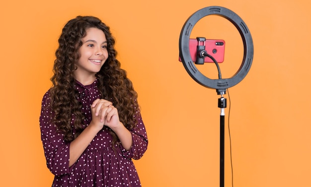 Glad child with long curly hair making video for blog