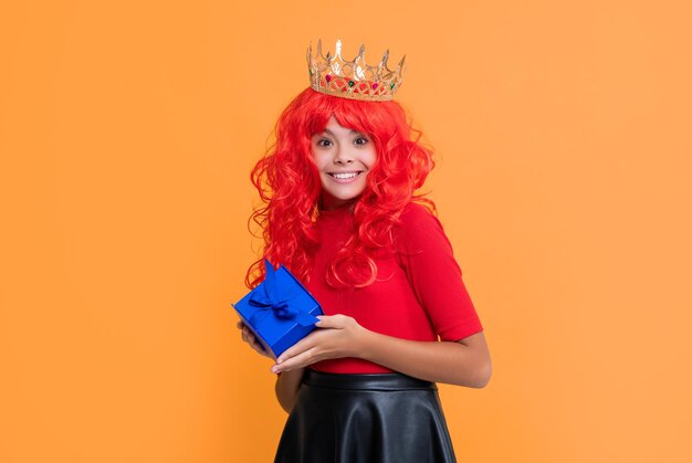 Glad girl in crown with present box on yellow background