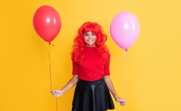 Glad girl with party balloon on yellow background