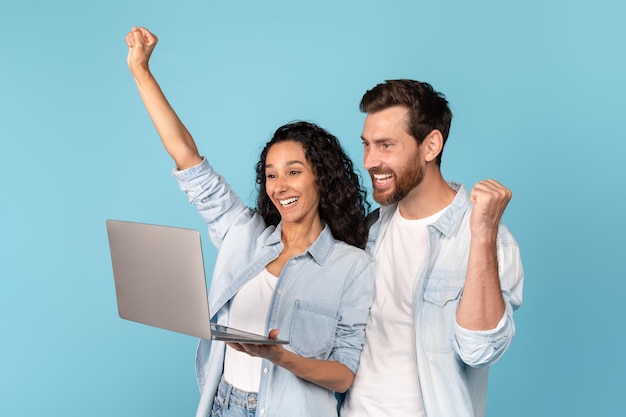 Glad millennial arab woman and caucasian male with beard with laptop rejoice and celebrate victory and success