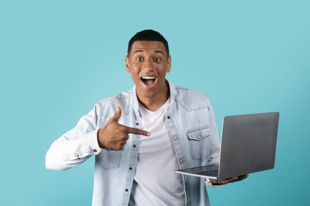 Glad millennial black male in casual showing finger at laptop enjoy win