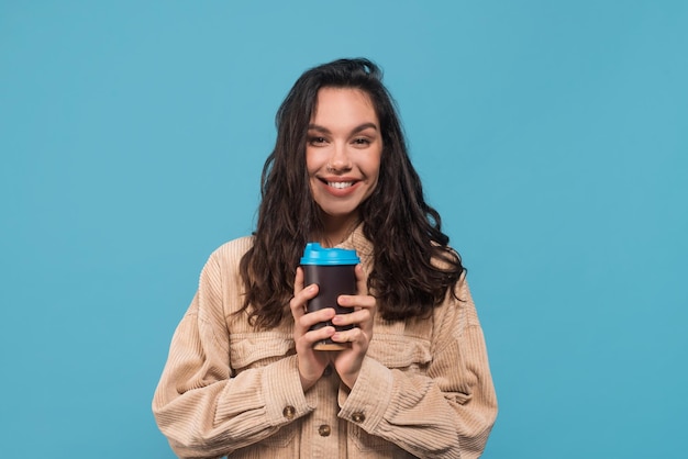 Glad millennial caucasian woman brunette student in casual holding cup of coffee takeaway or lady enjoy tea