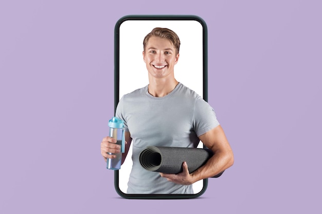 Радостный тысячелетний европейский мускулистый парень в спортивной одежде с ковриком и бутылкой воды, готовый к тренировке