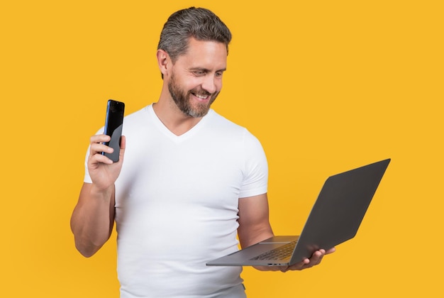 Glad multitasking man freelancing with laptop isolated on yellow multitasking freelancing man