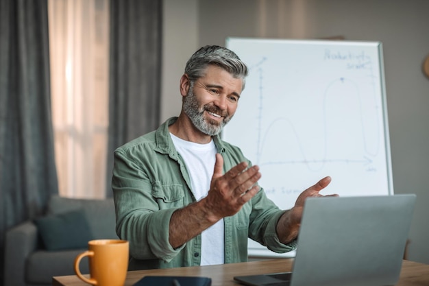 Glad old european male with beard has meeting with students or client at laptop shoot lecture