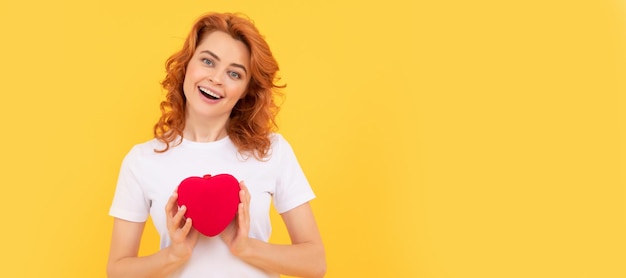 Glad redhead woman hold love heart on yellow background sweetheart Woman isolated face portrait banner with copy space