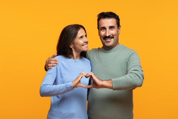 Glad senior european couple in casual make hard sign with hands sign