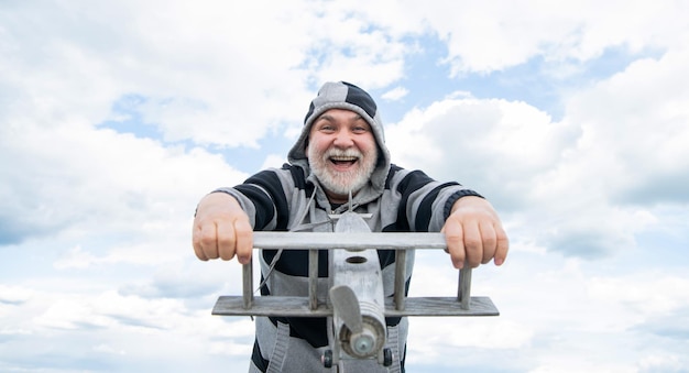 Glad senior man on sky background senior man at retirement senior retired man with toy plane