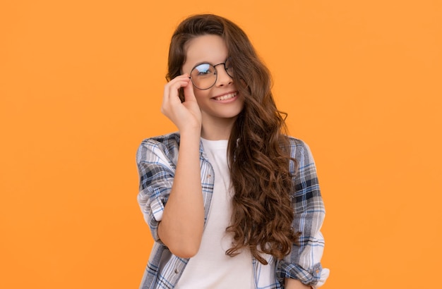 Glad teen child in checkered shirt and glasses on yellow background