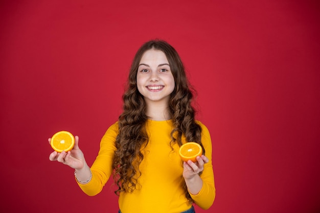 Glad teen child hold orange fruit on purple background