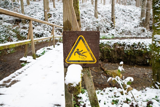 Glad waarschuwingsbord in het bos, houten brug bedekt met sneeuw, winterseizoen, pas op voor gevaar