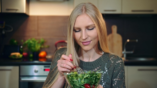 Donna felice che mangia insalata sana.