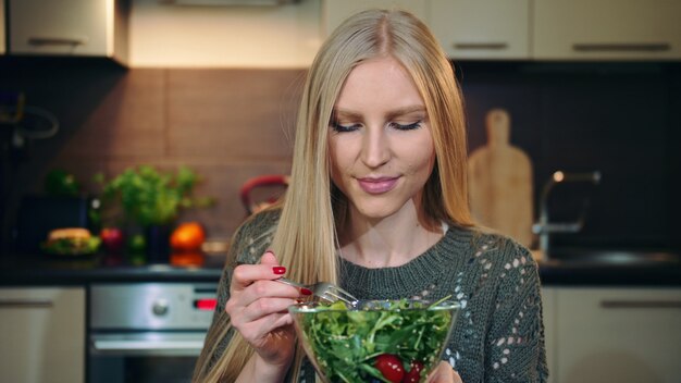 Donna felice che mangia insalata sana.