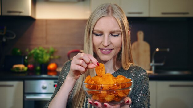 Glad woman eating potato chips.