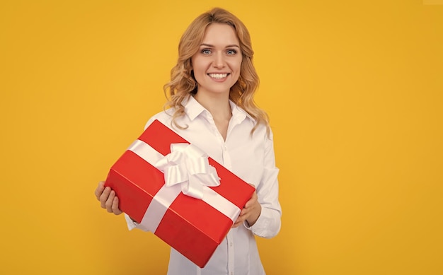 Glad woman with big present box on yellow background