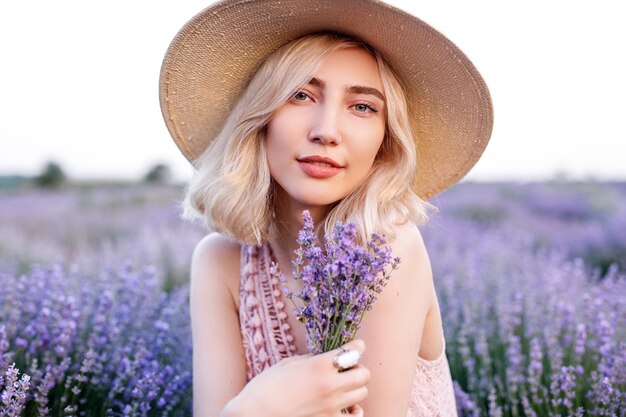 Glad woman with bouquet of lavenders in field