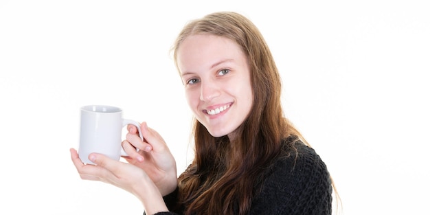 Photo glad young woman holds mug with coffee enjoys spare time stands against white background copy space area