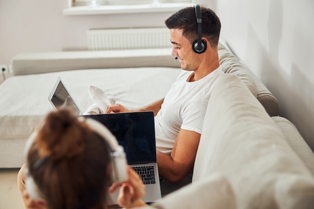 Gladsome gentleman looking at computer screen while sitting on couch