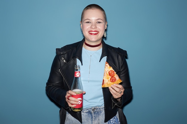 Foto glam rock giovane donna con una fetta di pizza e limonata