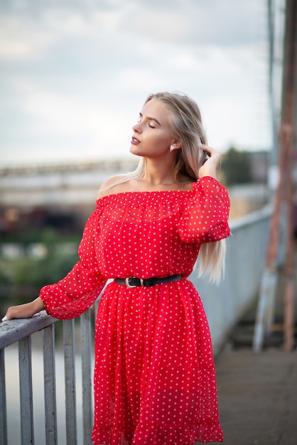 Glamor blonde woman with closed eyes posing on the bridge in the evening