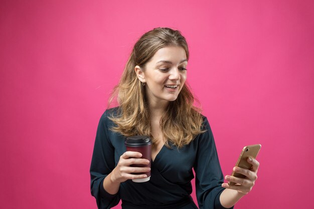 Glamor woman in a dark blue dress with a drink of coffee on a pink background