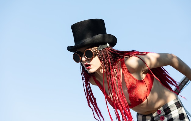 Glamorous girl with scarlet dreadlocks and welding glasses