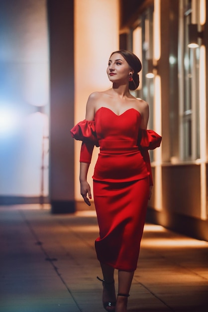 A glamorous woman in a red dress posing in the city. High quality photo