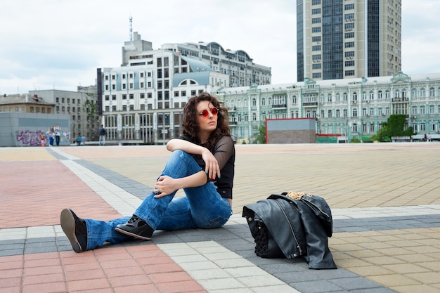 Glamorous young brunette woman in round red sunglasses having fun in the city