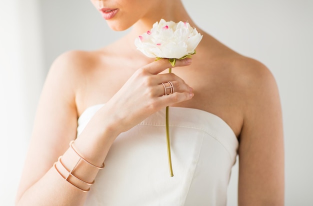 glamour, beauty, jewelry and luxury concept - close up of beautiful woman with golden ring and bracelet holding flower