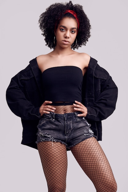 Glamour elegant zwart hipster tienermodel met krullend haar in korte broeken en kousen