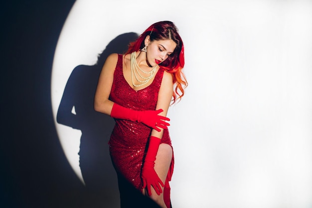 Фото Гламурная дама в красном платье позирует перед камерой на фоне студии