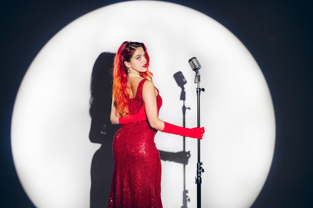 Photo glamour red haired woman holding a glass of champagne on the contrast background