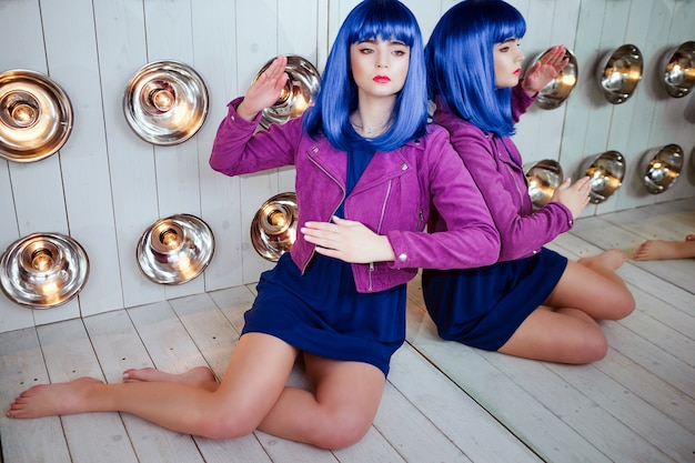 Foto glamour ragazza sintetica, finta bambola dall'aspetto vuoto e capelli blu è seduta in studio.