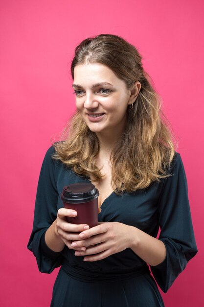 Glamour vrouw met een drankje van koffie op een roze achtergrond