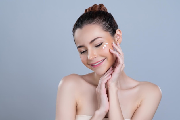 Glamoureuze vrouw die vochtinbrengende crème op haar gezicht aanbrengt voor een perfecte huid