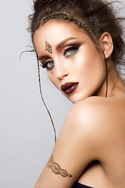 Glamourportret van mooi vrouwenmodel met gouden make-up en romantisch kapsel.