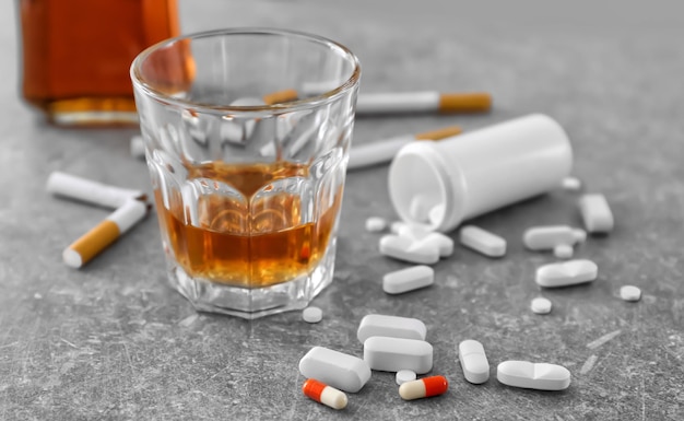 Glas alcohol sigaretten en drugs op tafel Concept van slechte gewoonten