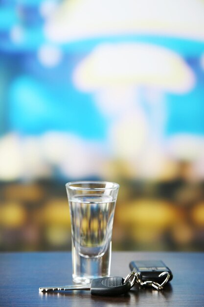 Glas alcoholische drank en autosleutel op houten tafel op lichte achtergrond