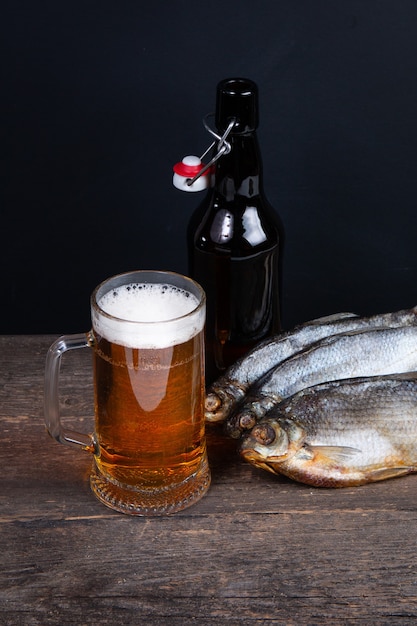Glas bier, droge vis en bierfles op een zwarte